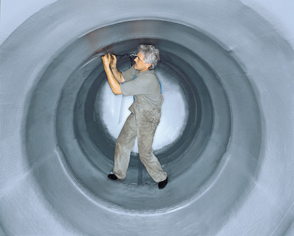 Innenansicht von Gebrauchtbeh&auml;lter mit grauer Leckschutzauskleidung; Monteur kontrolliert den Sitz der Innenh&uuml;lle