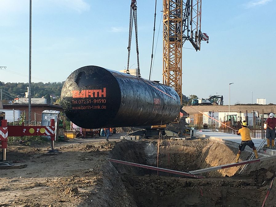 an Kran h&auml;ngender schwarzer Wassertank der Firma Tank und Apparate Barth GmbH wird in Baugrube abgelassen